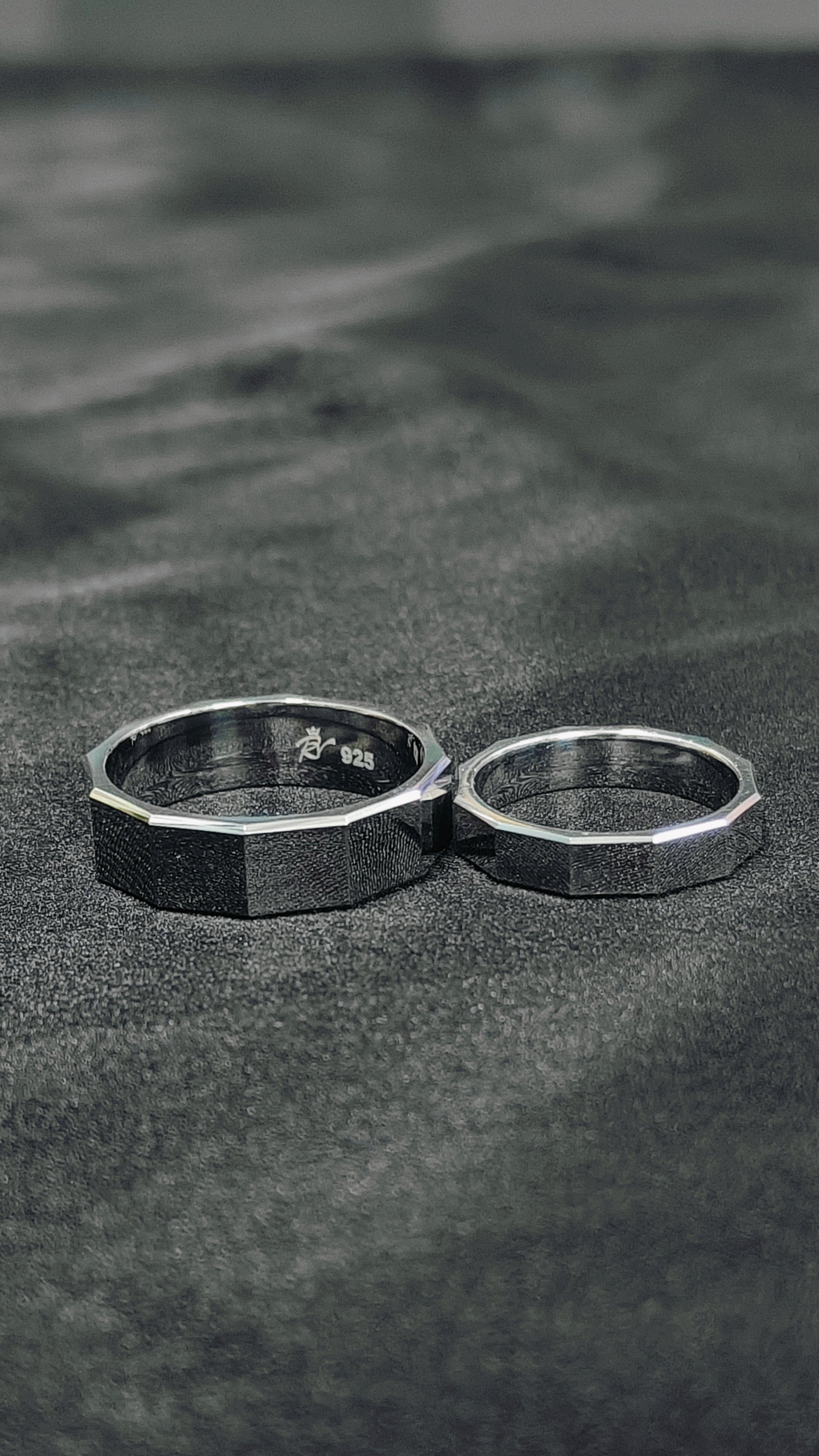 Two silver rings on a textured black surface